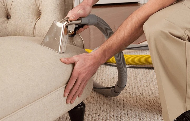 Well-dressed upholstery cleaning technician from Alec’s Carpet & Upholstery Cleaning LLC carefully cleaning a sofa in Hingham, Massachusetts