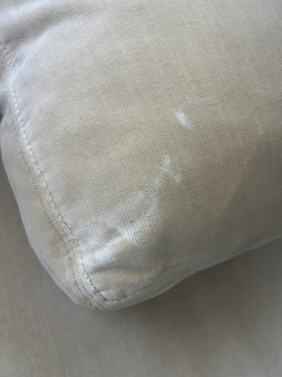 Close-up of beige chenille upholstery showing a light, distorted area from improper spot cleaning.