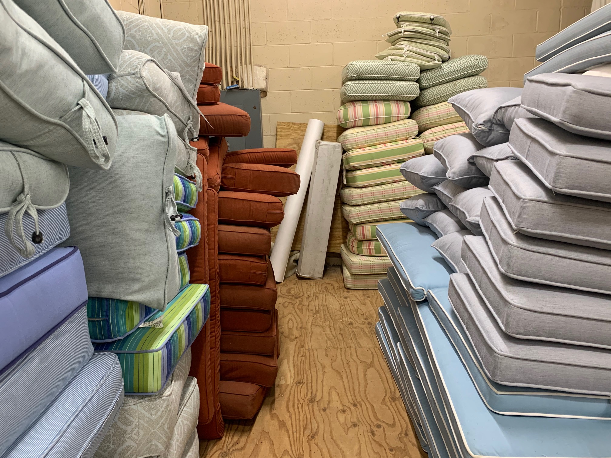 Outdoor furniture cushions at Alec's Carpet & Upholstery Cleaning's facility awaiting professional cleaning.