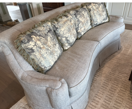 Professionally cleaned curved sofa with seat cushions properly positioned after drying.